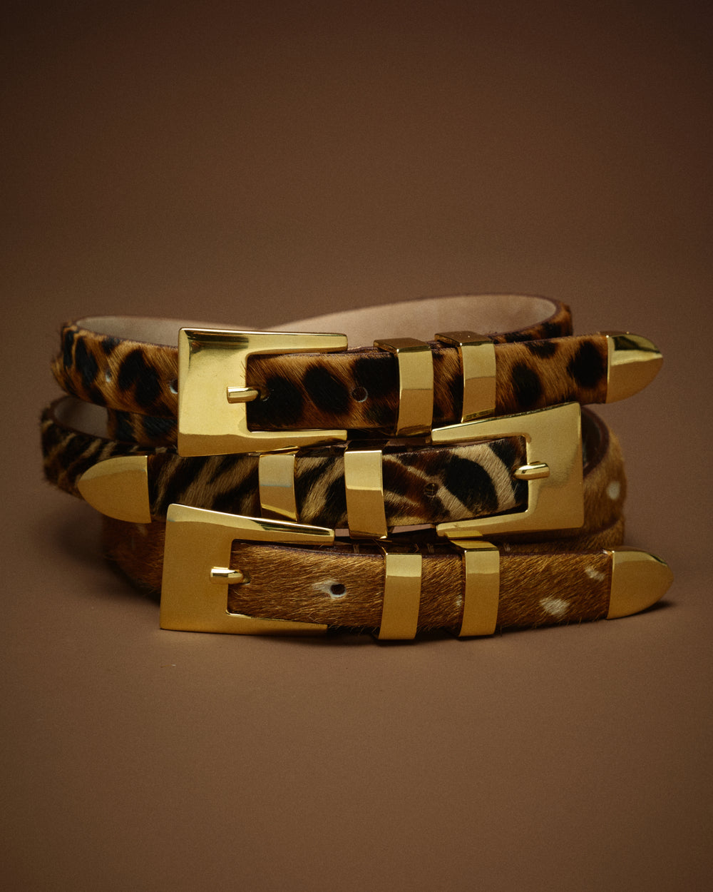 Three animal-print belts with gold-tone buckles and matching gold-tone metal accents, stacked together